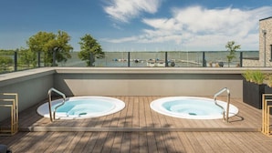 A rooftop terrace with two hot tubs, a wooden deck, and a view of the marina and boats. - Stunning home in Lembruch/Dümmer See with sauna (Lembruch/Dümmer See)