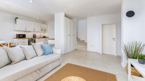 A modern apartment with a living area, kitchenette, and a staircase leading to another level.