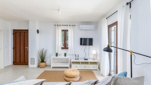 A modern living room with a sofa, a TV, a lamp, and a potted plant.