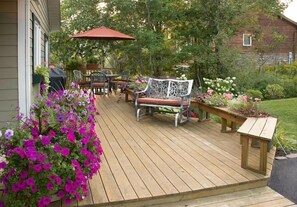 Relax on the deck surrounded by lush greenery and flowering plants.