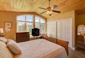 Relax in this serene bedroom with a large bed, ceiling fan, and stunning views of the surrounding greenery.