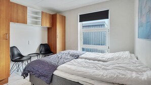 A bedroom with a bed, a desk, two chairs, and a wardrobe.