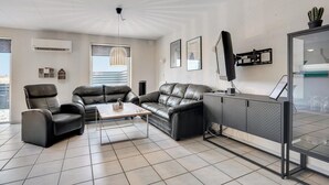 A modern living room with a leather sofa, a coffee table, and a glass partition.