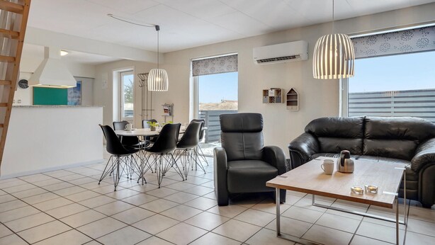 A modern living room with a dining area, leather furniture, and large windows offering a view.