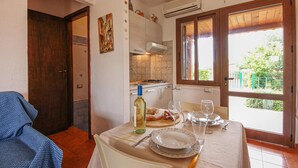 A dining area with a table set for two, a bottle of wine, and a painting on the wall.