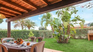 A covered outdoor dining area with a table set for four, surrounded by chairs.