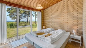 A bedroom with a large bed, a wooden ceiling, and a brick wall. - Cozy home in Vesløs with house sea view (Vesløs)