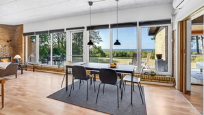 A spacious room with a large dining table, chairs, and a view of the outdoors. - Cozy home in Vesløs with house sea view (Vesløs)