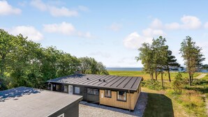A modern building with a flat roof, a gravel driveway, and a view of the sea. - Cozy home in Vesløs with house sea view (Vesløs)