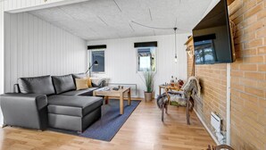 A modern living room with a sectional sofa, a small table, and a fireplace. - Cozy home in Vesløs with house sea view (Vesløs)