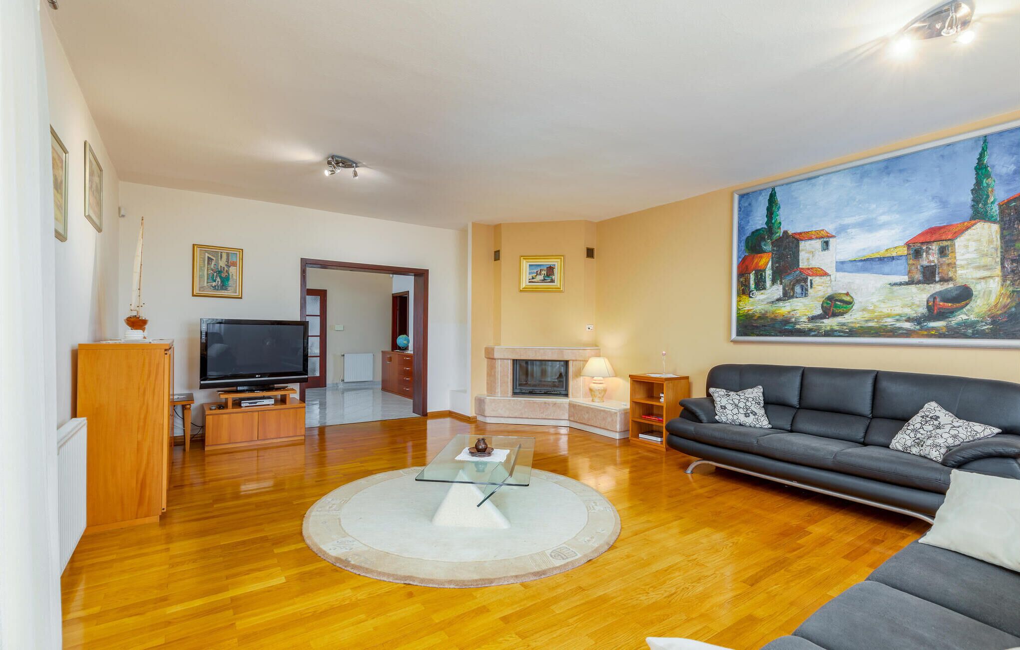 A living room with a fireplace, a large painting, a sofa, and a television.