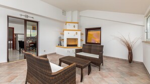 A spacious living area with wicker furniture, a fireplace, and a view of the outdoors.