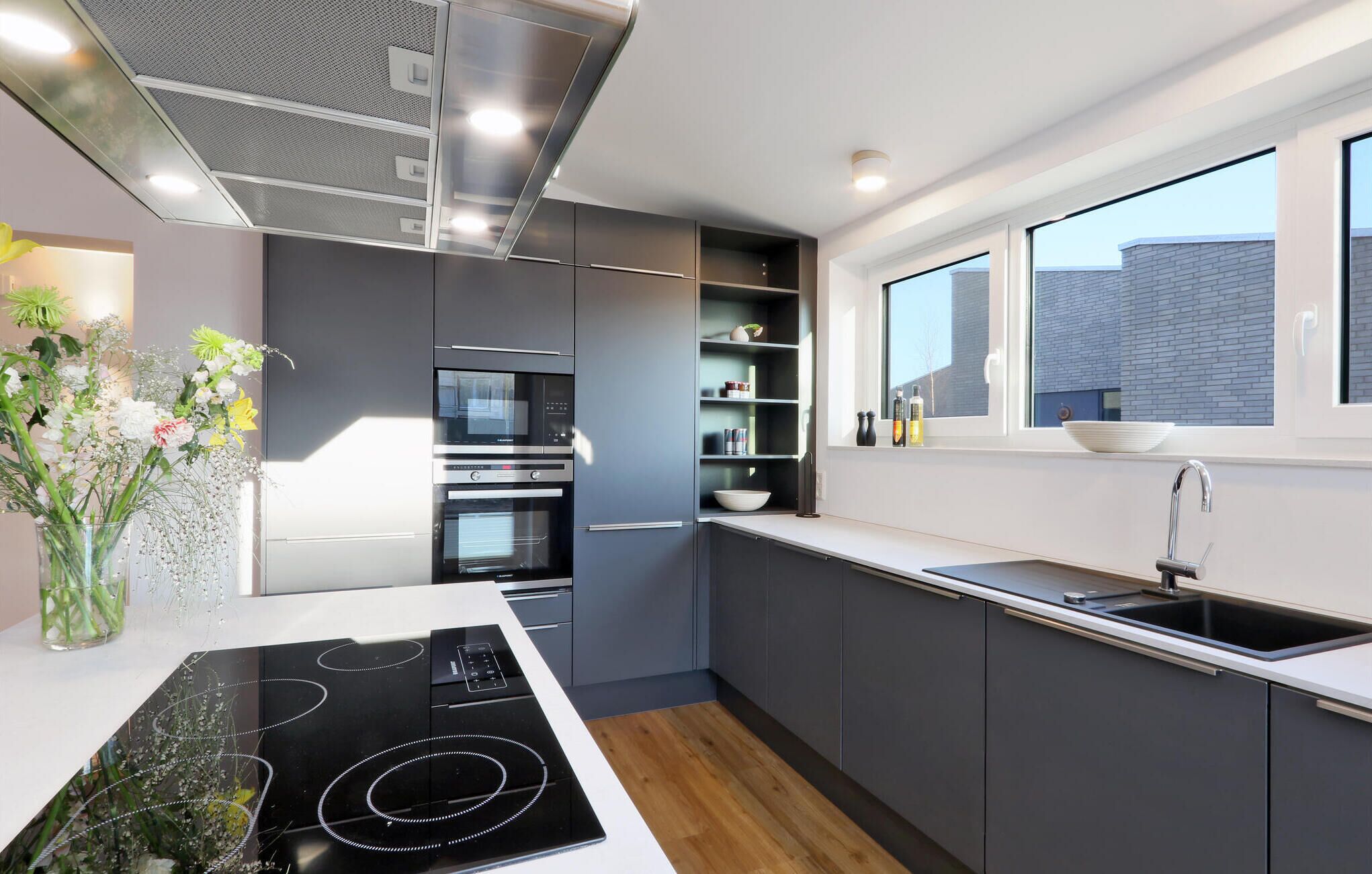 Una cucina moderna con forno integrato, piano cottura e finestra vista su un edificio in mattoni.