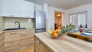 Eine moderne Küche mit Einbaukühlschrank, Spüle und Obstschale auf der Arbeitsplatte.