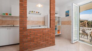 Eine moderne Küche mit Ziegelwand, einem Essbereich mit Glastür zum Balkon und Blick ins Freie.