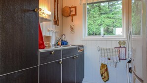 A kitchen with a wooden cabinet, a window with a view of trees, and a hanging cloth. - 3 bedroom lovely home in Helvik (Helvik)