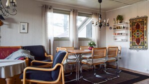 A dining area with a wooden table and chairs, a chandelier, and a view of the outdoors through large windows. - 3 bedroom lovely home in Helvik (Helvik)