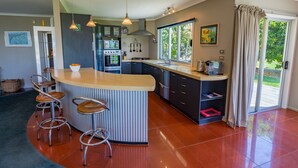Een moderne keuken met een centraal eiland, barstoelen, roestvrijstalen apparatuur en een groot raam met uitzicht op de omgeving.