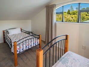 Une chambre avec un lit simple, une fenêtre donnant sur un espace verdoyant et un rideau.