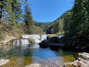 Un paisaje natural con cascada, agua cristalina y bosque circundante.