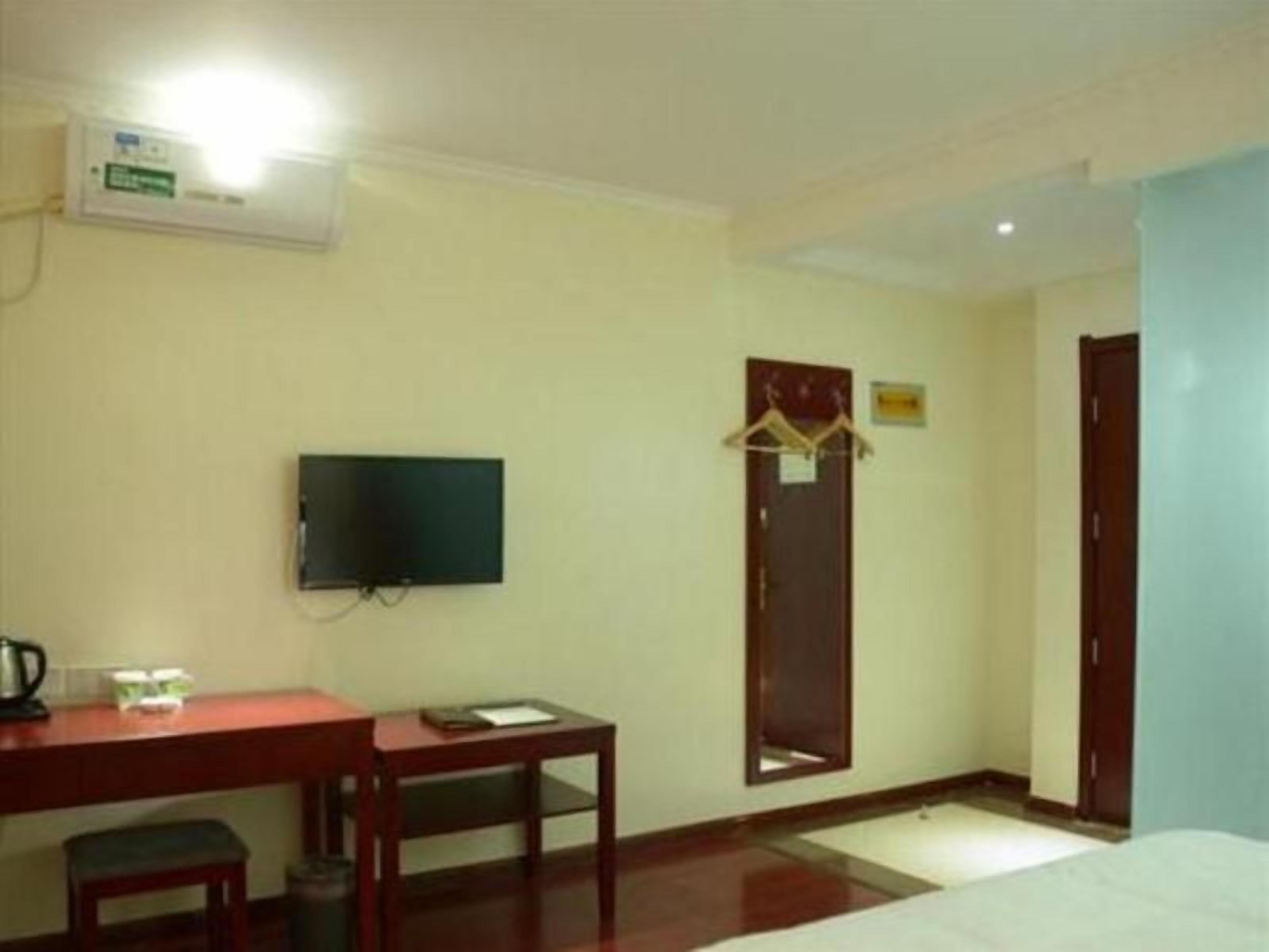 Una camera d'albergo con un letto, una scrivania con una sedia, una televisione, un armadio e una porta.