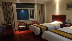 Een hotelkamer met twee bedden, een bureau, een stoel en een raam met gordijnen.