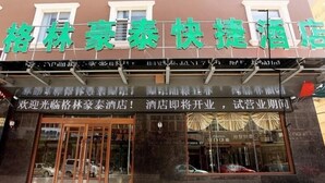 Un hotel con un cartel en idioma extranjero, ventanas amplias y una alfombra roja que lleva a la entrada.