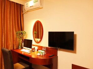 A hotel room with a wooden desk, a computer, a TV, a mirror, and a plant. - Greentree Inn Chifeng Linxi Ronglin Homeland Express Hotel (Chifeng)