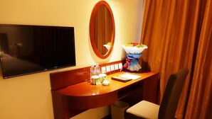 A hotel room with a wooden desk, a television mounted on the wall, a small trash bin, and a chair. - Greentree Inn Chifeng Linxi Ronglin Homeland Express Hotel (Chifeng)