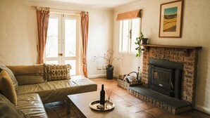 A cozy living room with a sofa, a fireplace, and a window with curtains.