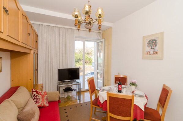 A furnished room with a television, dining table, chairs, and a sofa.
