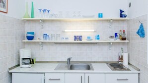 A kitchen with white cabinets, a stainless steel sink, and a coffee maker. - Plavi Zal (Dubrovnik)