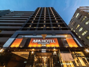 El APA HOTEL, con una fachada moderna, amplias ventanas y una entrada destacada.