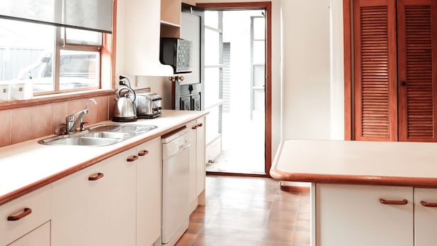 A kitchen with white cabinets, a wooden countertop, a sink, and a window.