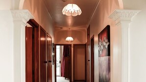 A hallway with a carpeted floor, wooden doors, and a ceiling light fixture.