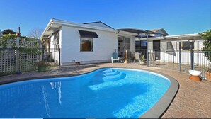 A modern house with a swimming pool, a fenced patio, and a covered outdoor area.