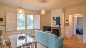 Una sala de estar con un sofá azul claro, una mesa de comedor con sillas, una chimenea y un televisor.