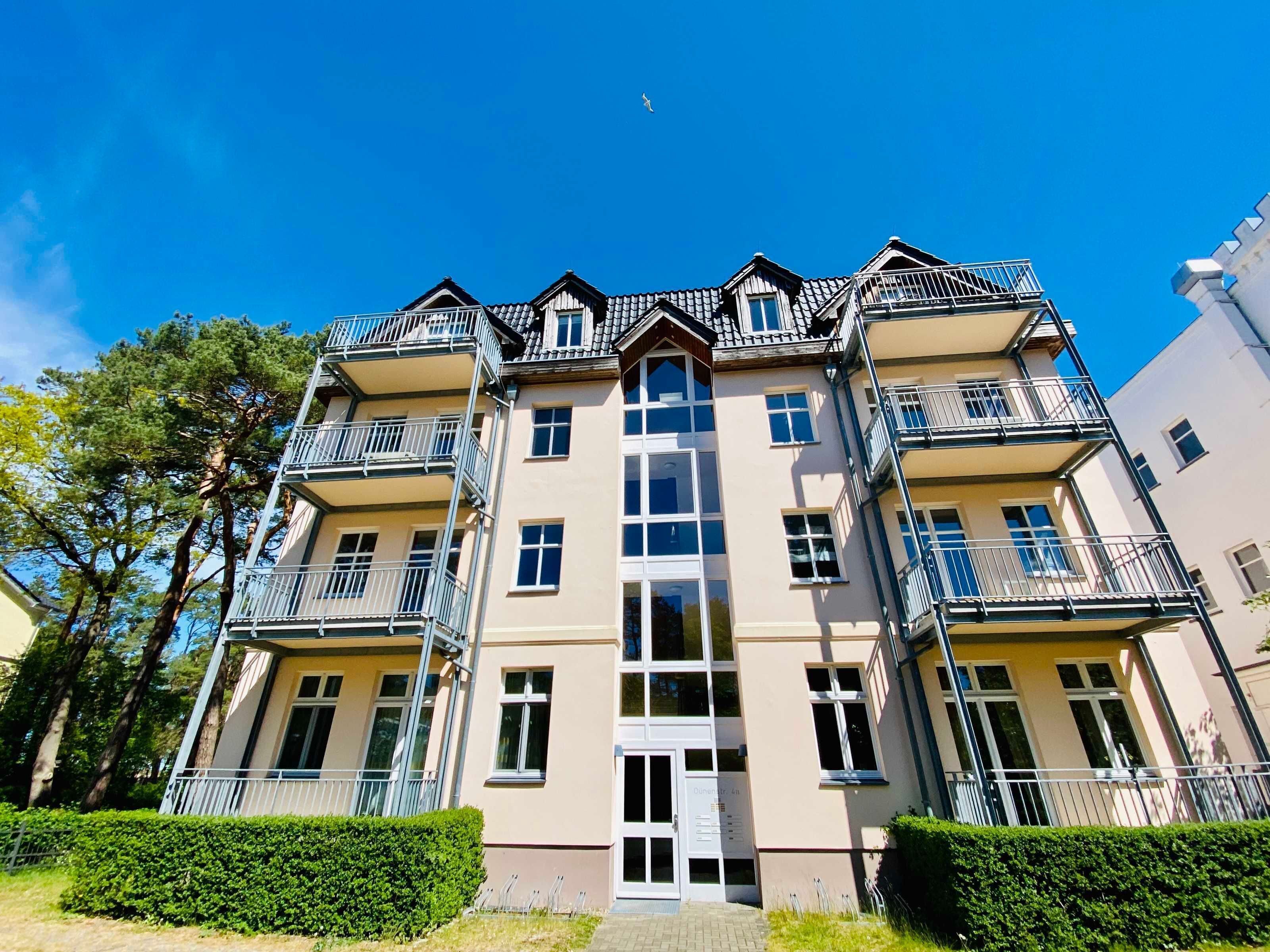 A multi-story residential building with balconies, large windows, and a central entrance.