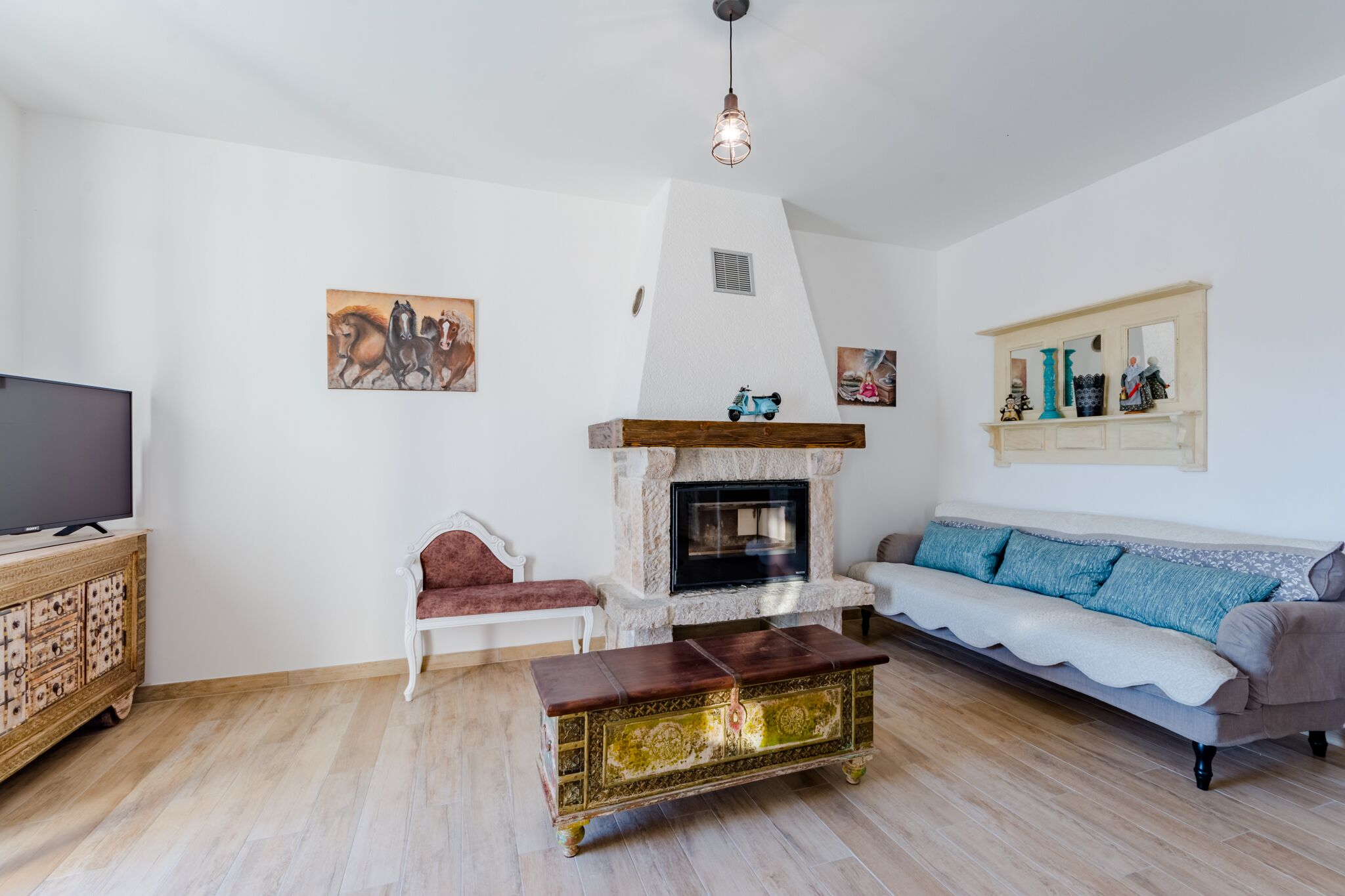 A living room with a fireplace, a sofa, a red chair, and a wooden cabinet.