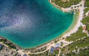 An aerial view of a coastal area with a clear beach, boats, and buildings. - Apartment Porat (Drage)