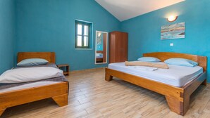 Une chambre à coucher avec deux lits en bois, une armoire, une fenêtre et un tableau accroché au mur.