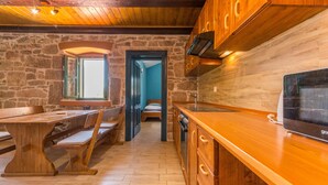 Une cuisine rustique avec des meubles en bois, un mur en pierre et un coin repas avec des bancs.
