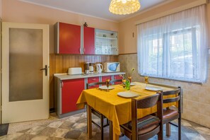 A compact kitchen with a dining table, chairs, and a window with curtains.