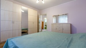 A bedroom with a bed, a wardrobe, a dresser, and a mirror. - Apartment Eugen (Crikvenica)