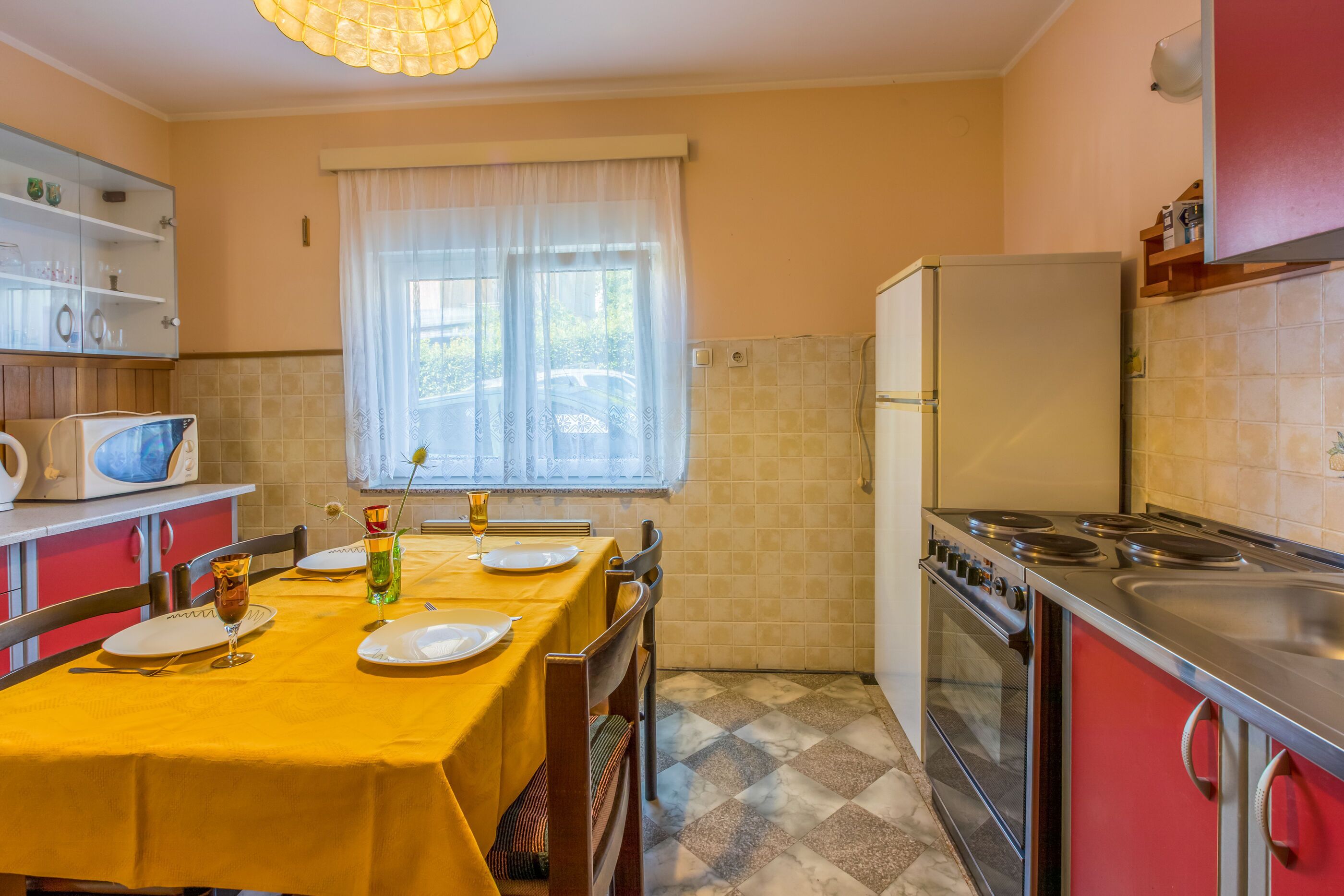 A compact kitchen with a dining table set for two, a refrigerator, and a stove.