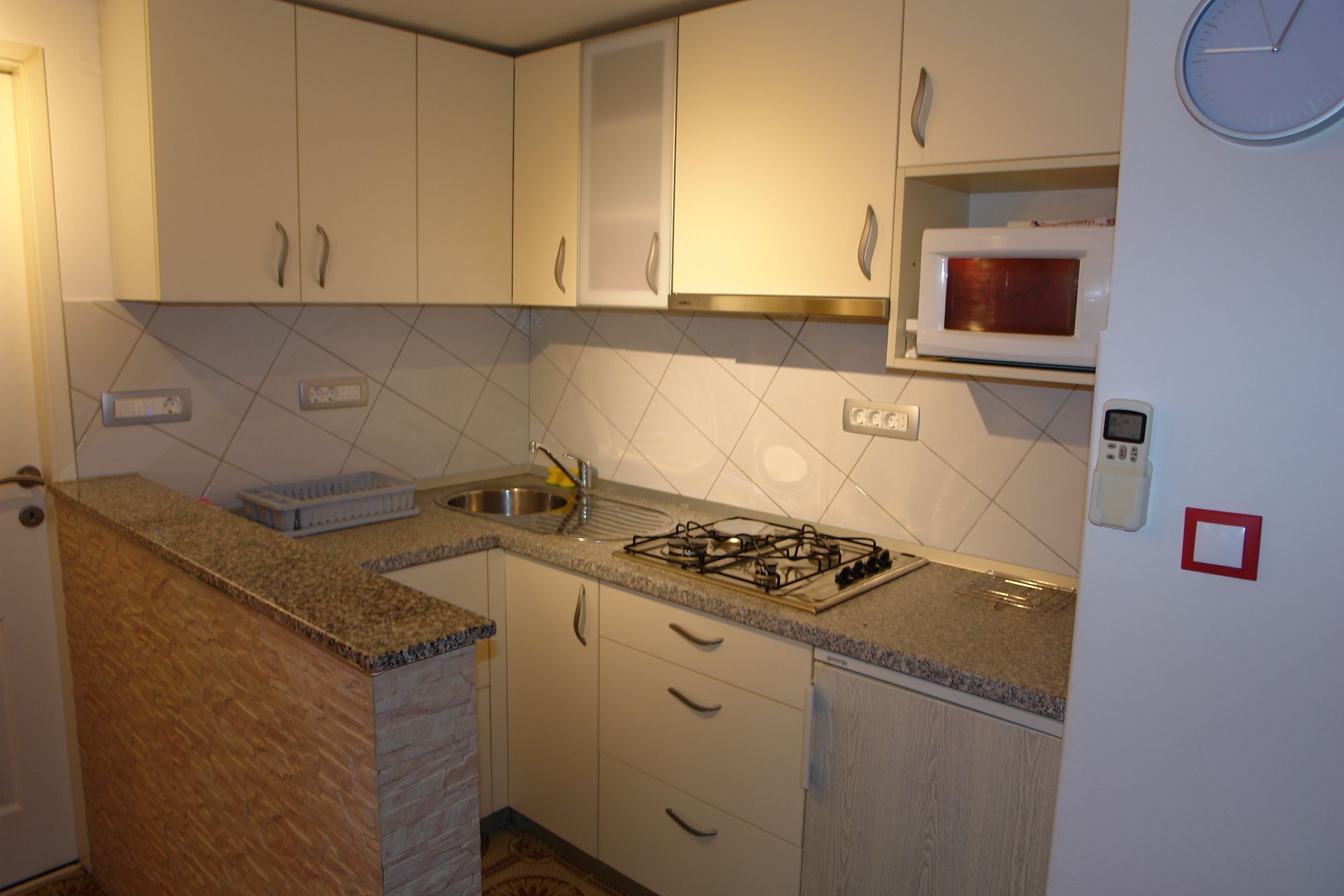 A kitchen with white cabinets, a gas stove, a microwave, and a sink.