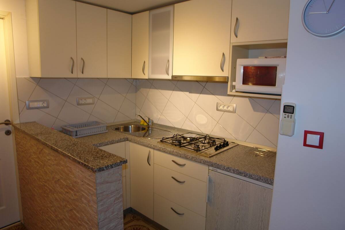 A kitchen with white cabinets, a gas stove, a microwave, and a sink.