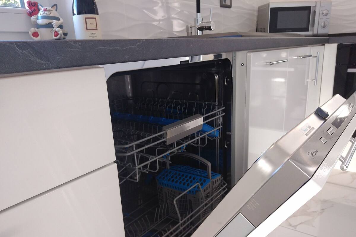 Una cucina moderna con lavastoviglie integrata, forno a microonde e forno in acciaio inossidabile.