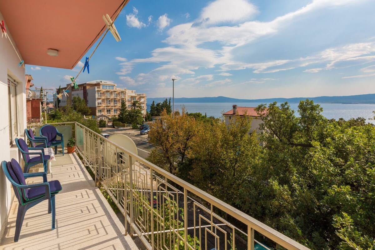 Un balcone con sedie, vista su un corso d'acqua e edifici sullo sfondo.