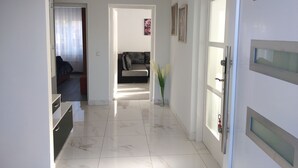 A hallway with a sofa and a vase of flowers, leading to a room with a bed. - Apartment Novakovic (Crikvenica)